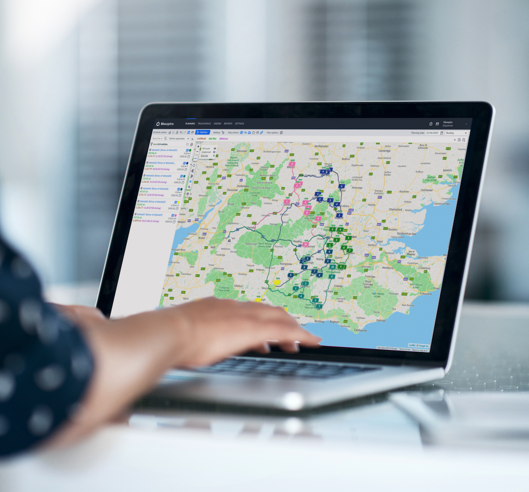 A closeup of a laptop with hands rested on the keyboard. The laptop shows a map on screen with several locations pinned on the Maxopatra software