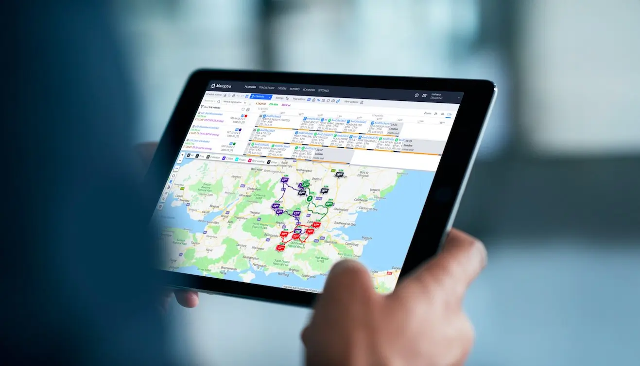 Close-up of a hand holding a tablet with a map on the screen.