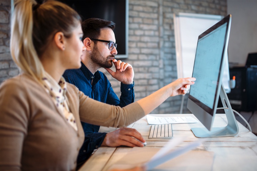 Office workers discussing reports on a computer screen