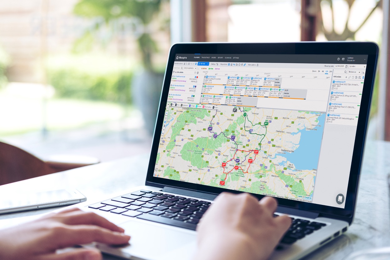 A closeup of a laptop with hands rested on the keyboard. The laptop shows a map on screen with several locations pinned on the Maxopatra software