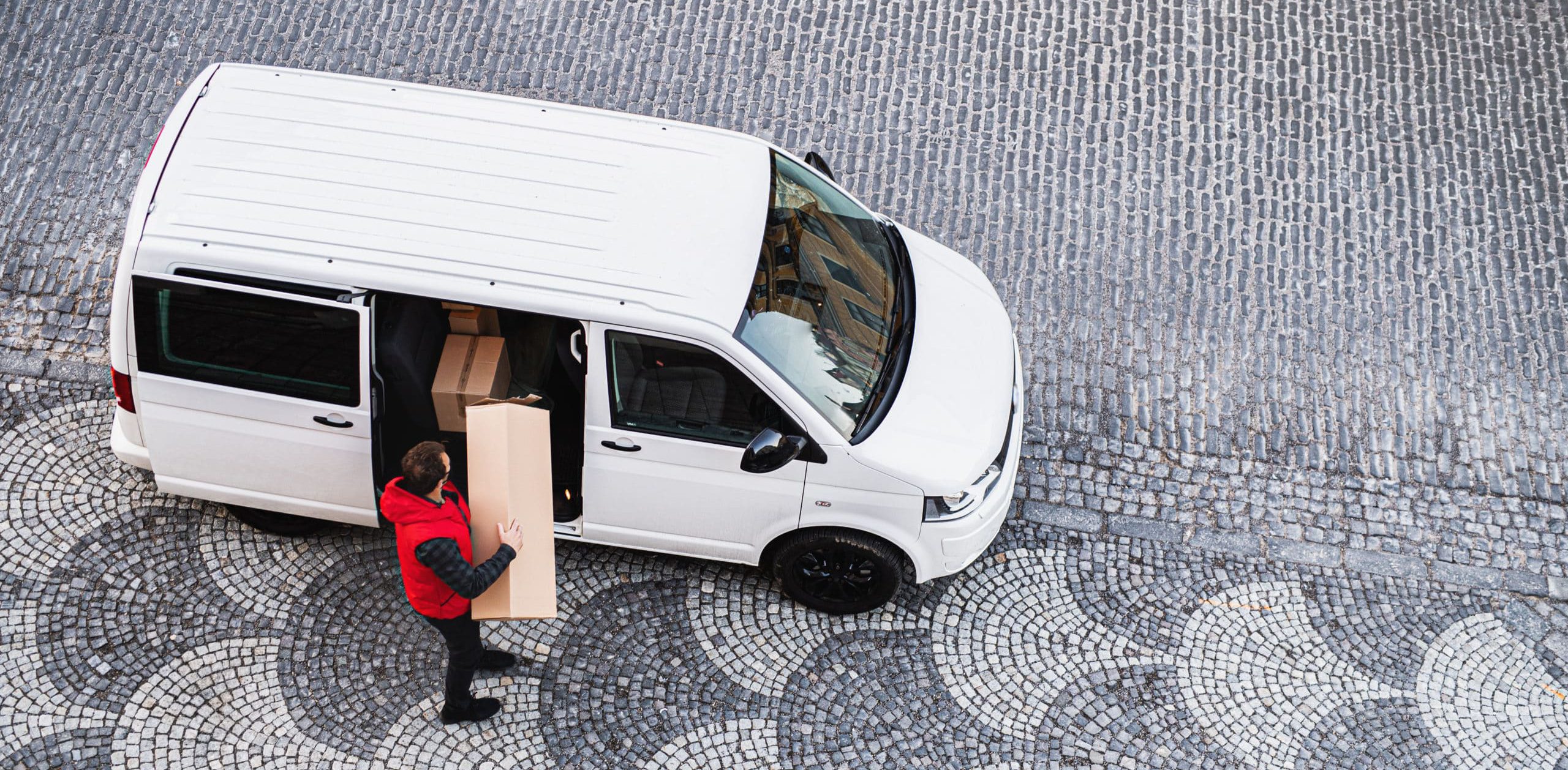 An aerial view of delivery man courier with face mask delivering parcel box in town.