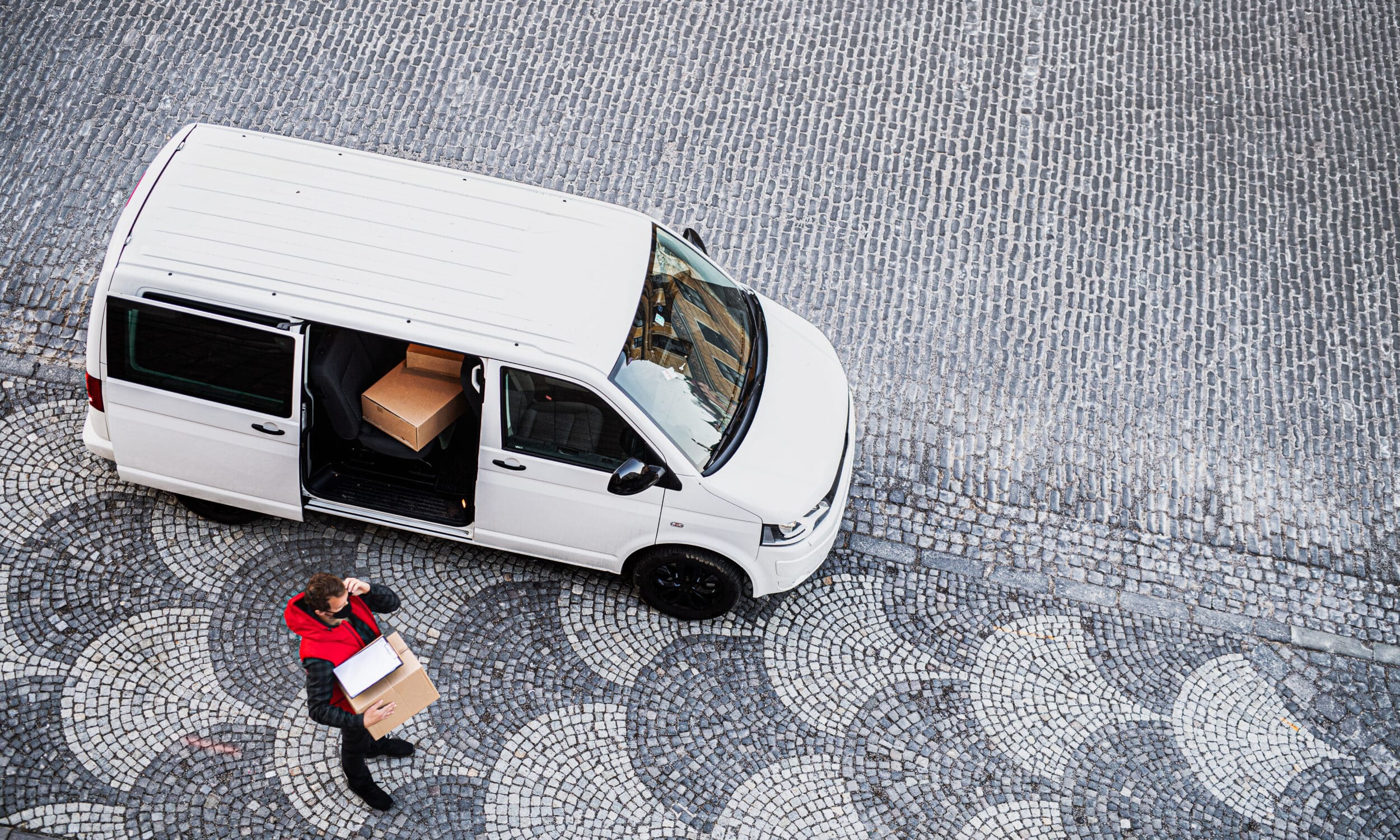 Delivery man with parcels outside his van, navigating deliveries using route planning software