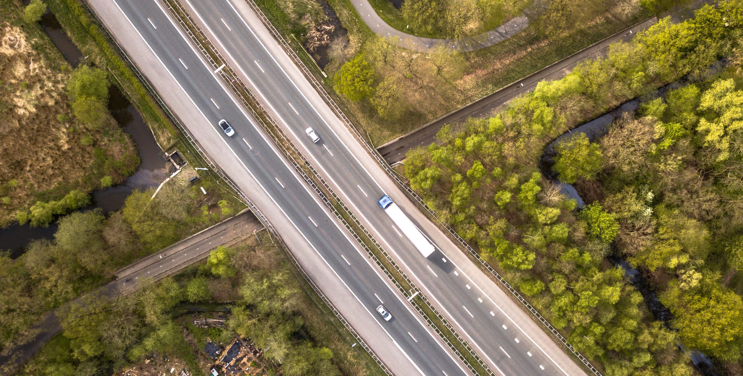 Aerial view of four lane motorway with emergency lane and moderate traffic during rush hour
