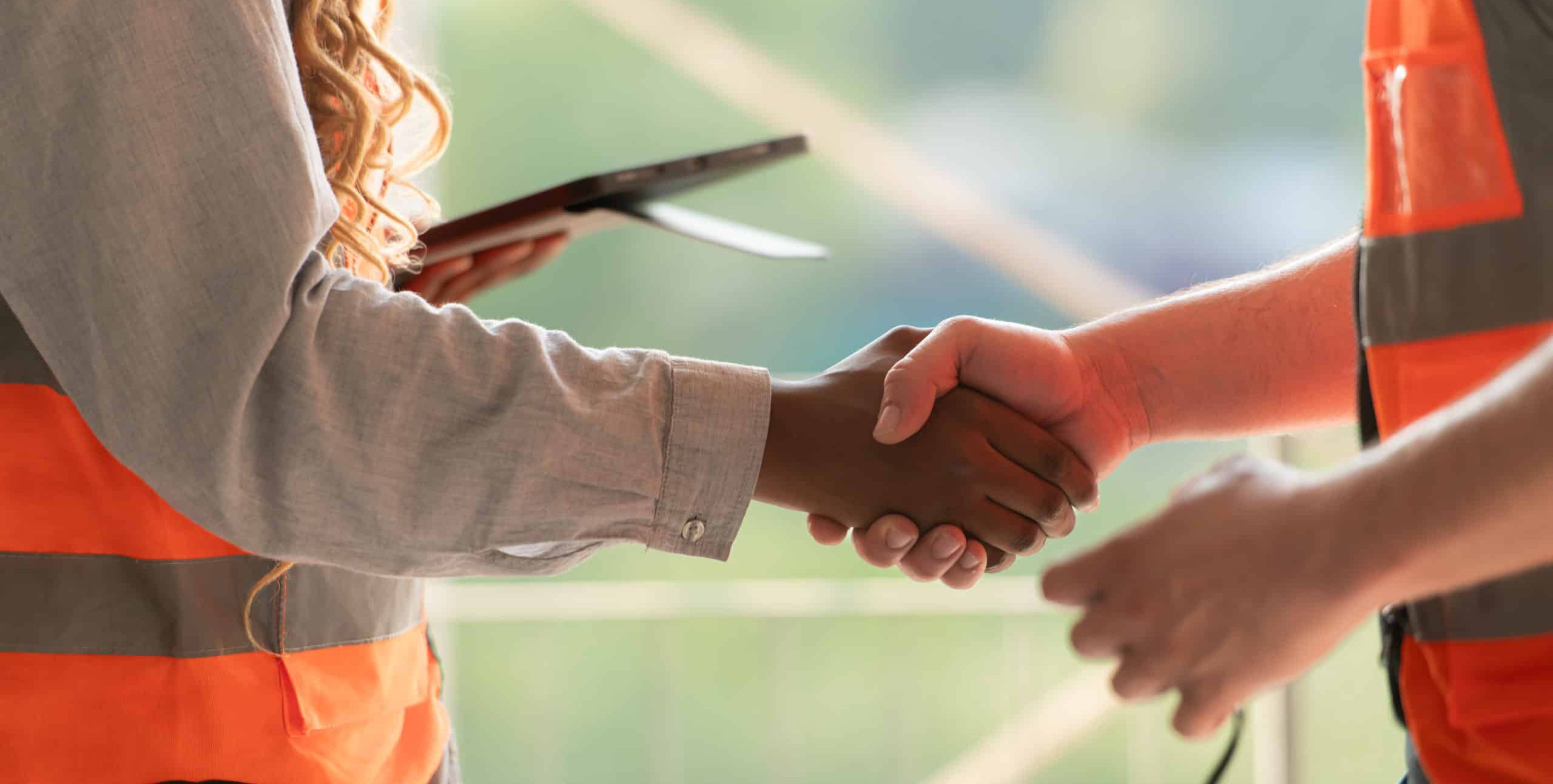 Two people in high vis jackets shaking hands.