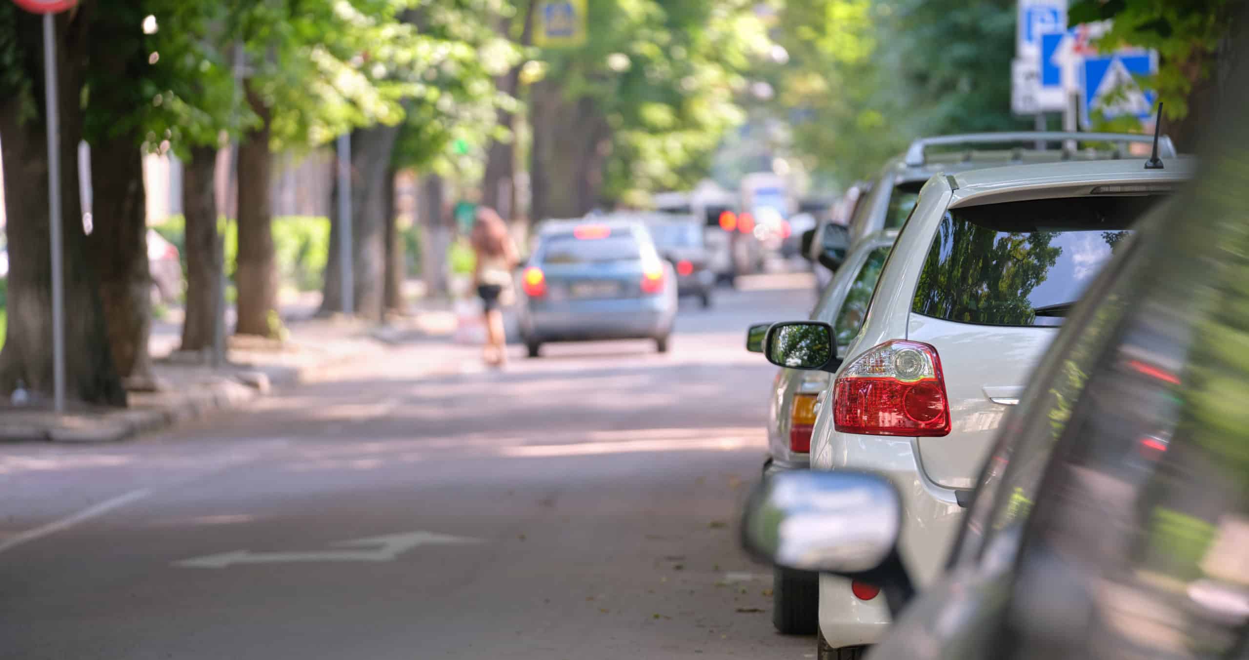 City traffic with cars parked in line on street side.