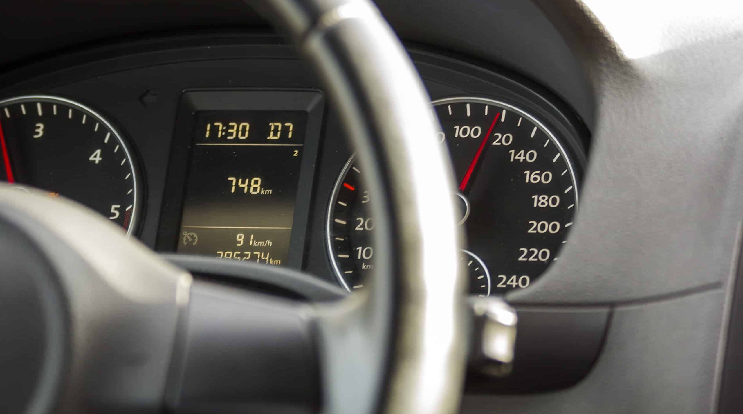 Close up interior view of modern luxurious black car. Dashboard, steering wheel, speedometer.