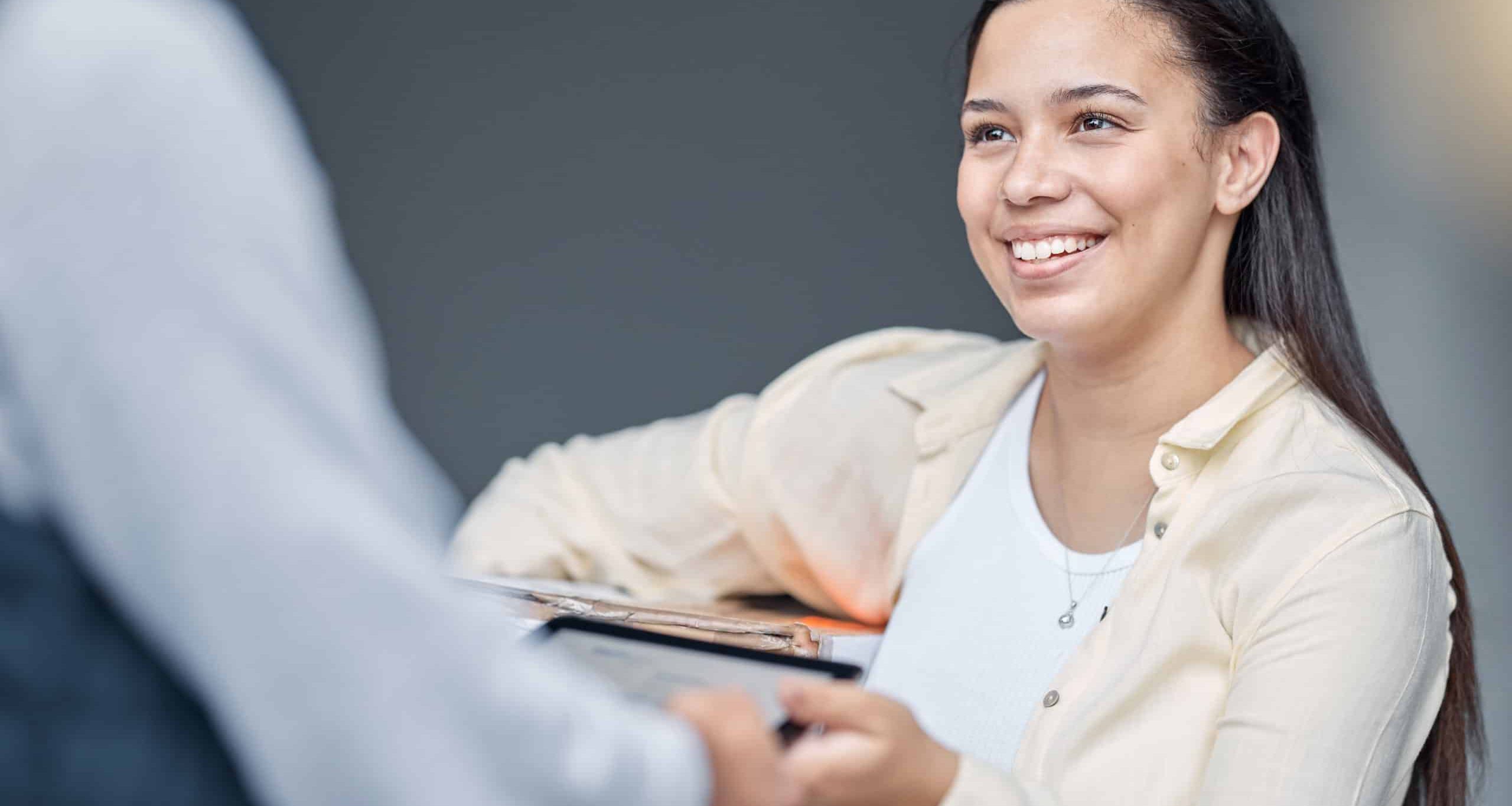 Smiling woman receiving a delivery and signing for it on a mobile device