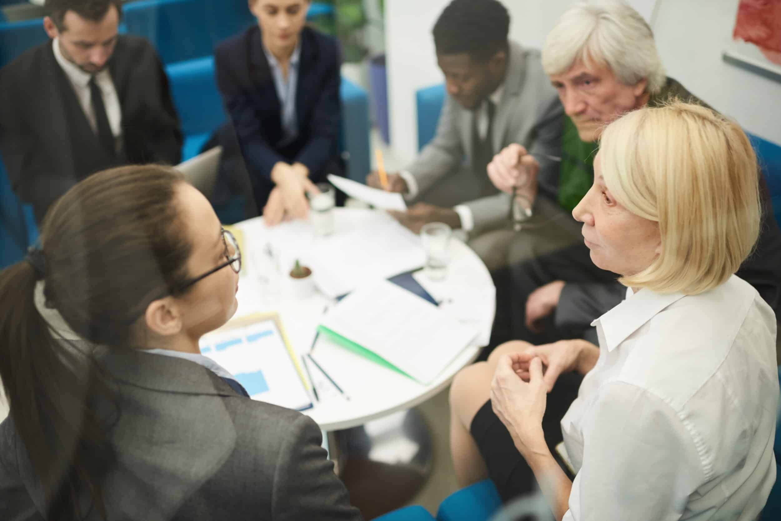 High angle photo of a business meeting around a round table, discussing potential risks and challenges of route optimisation