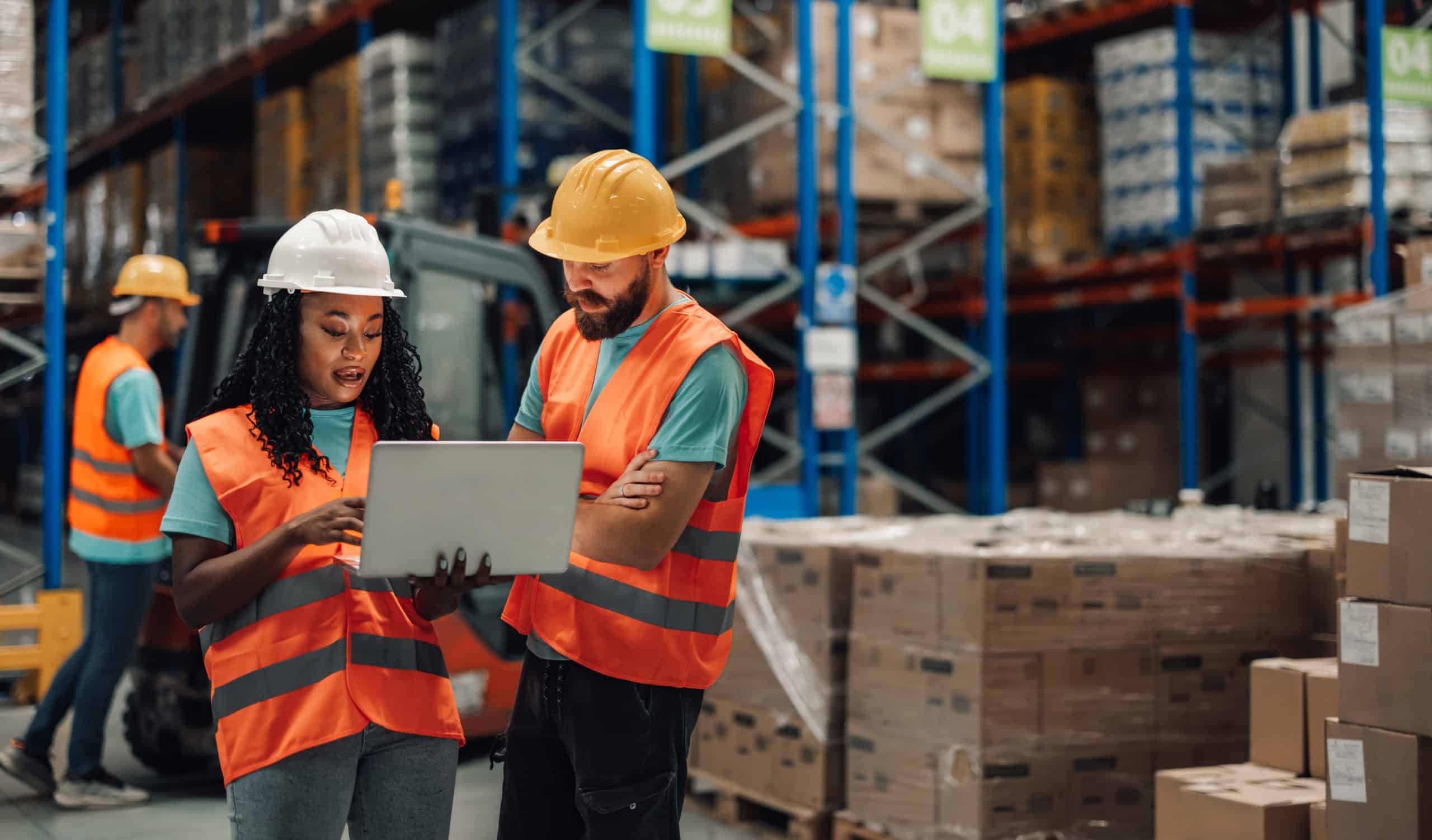 Two warehouse workers using laptop in warehouse