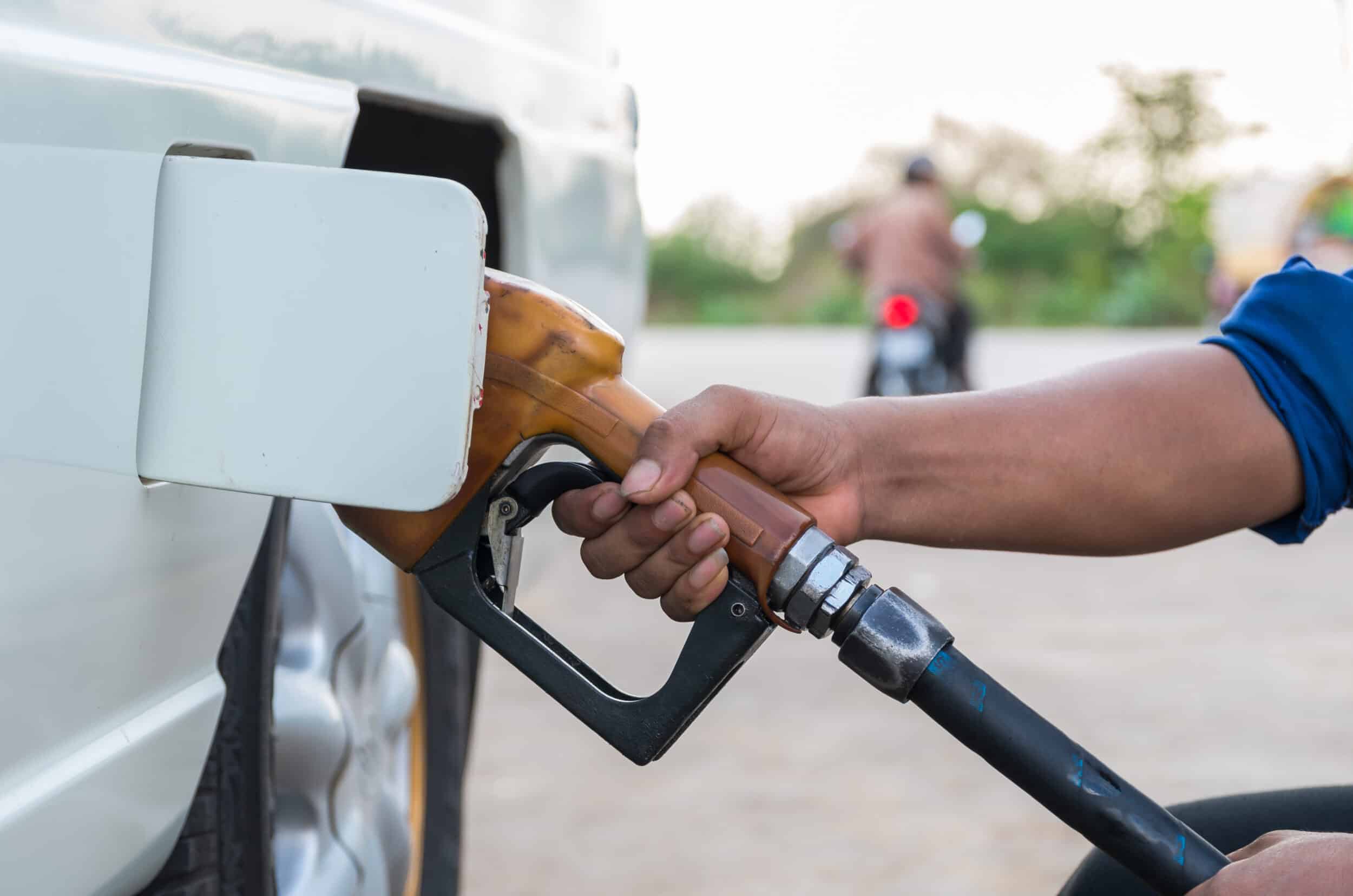 Close up of a person filling up a white van at a petrol station - holding the petrol nozzle.