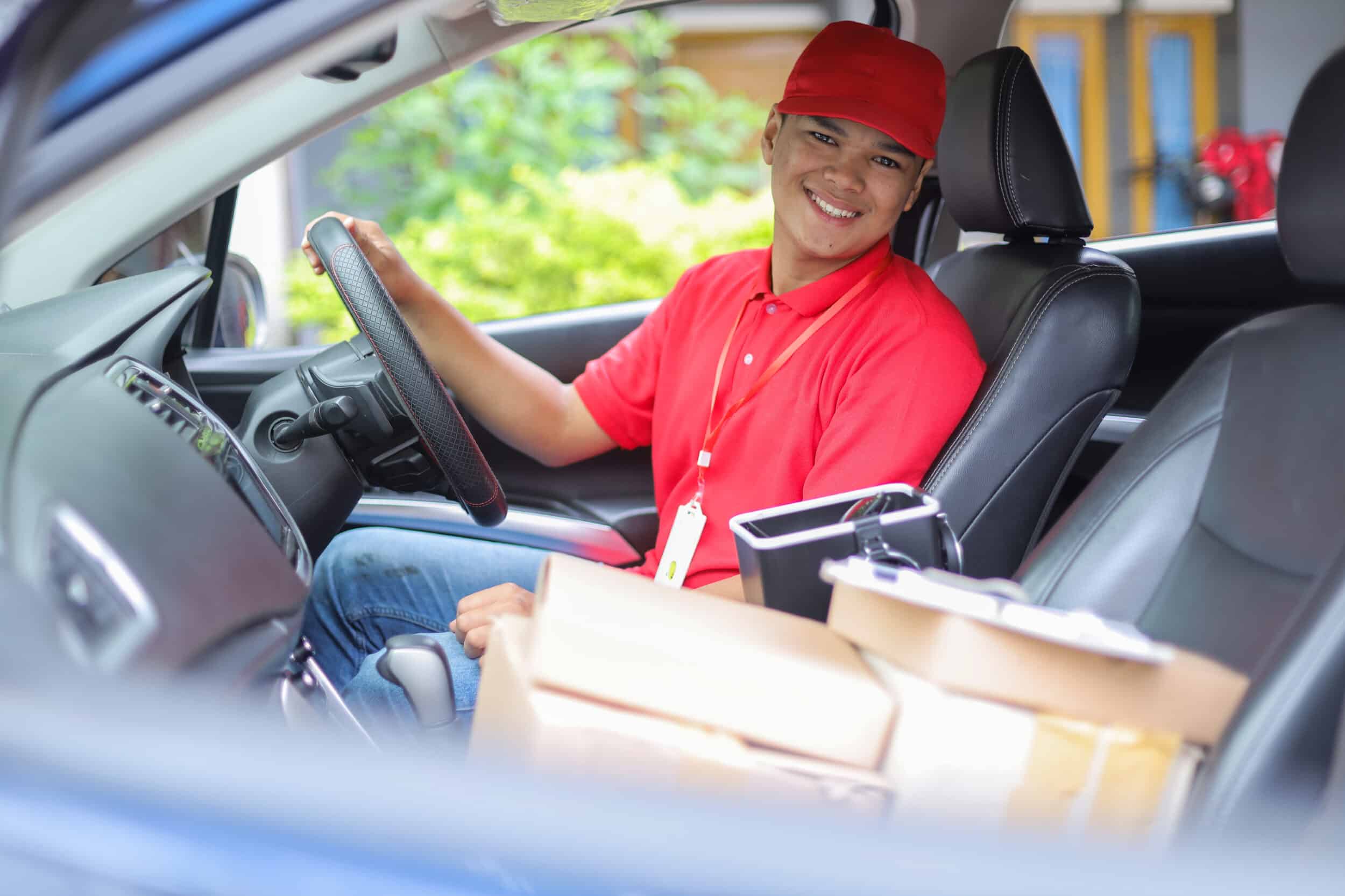 Smiling delivery driver inside their delivery van, ready to deliver parcels with route planning software