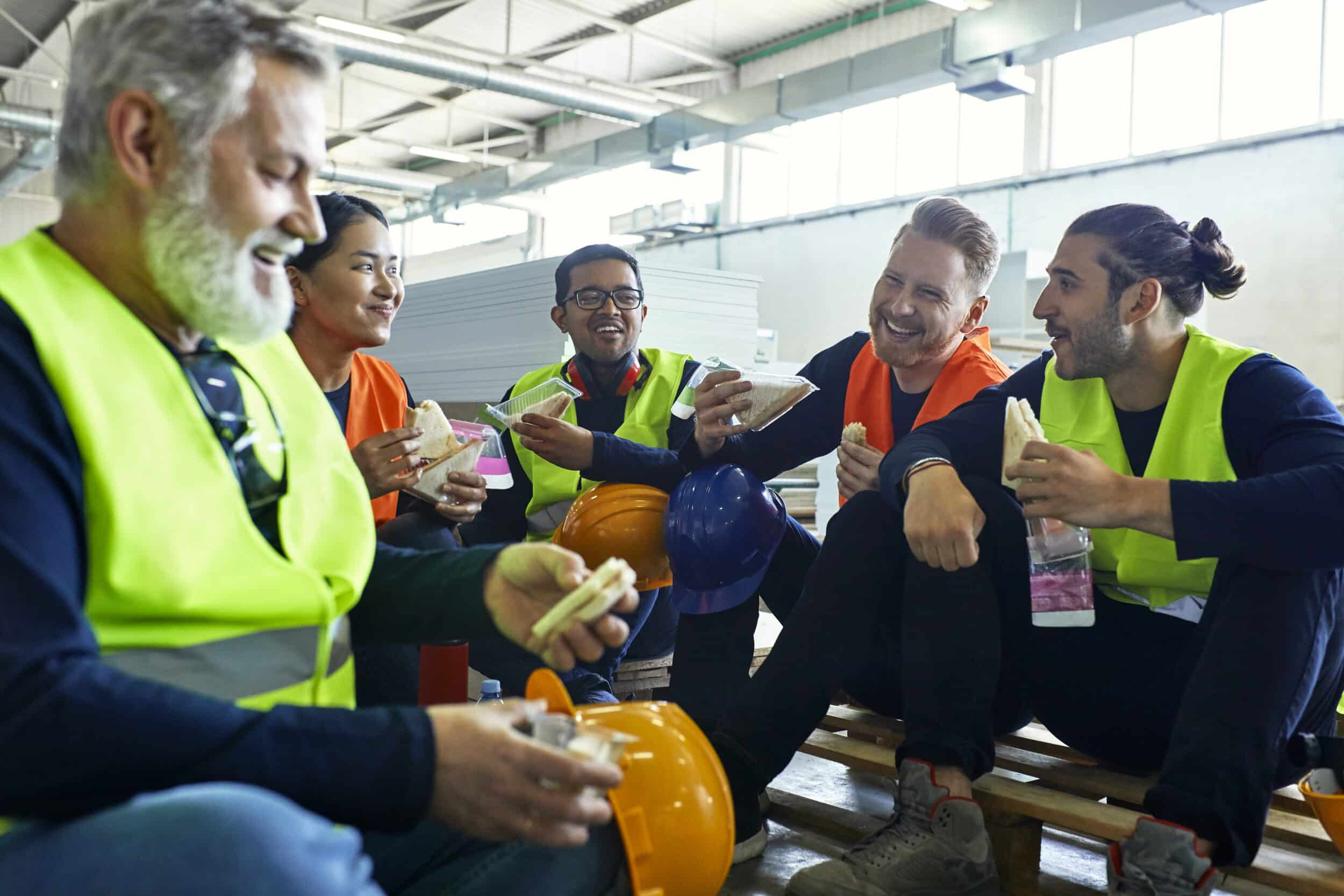 Group of delivery drivers having lunch together, smiling and laughing
