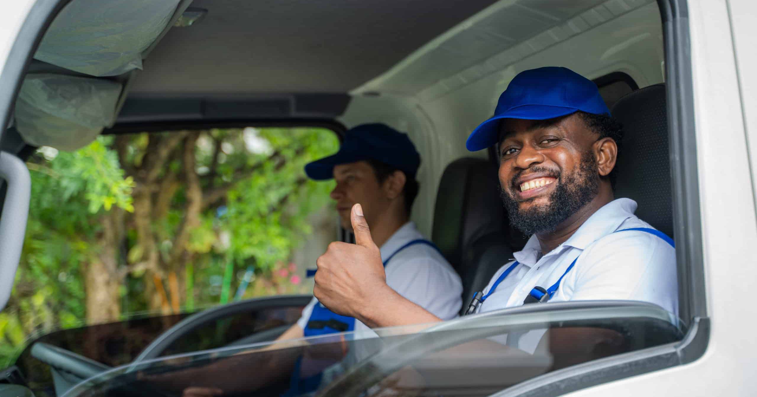 Two delivery men in van, one is looking our the window and giving a thumbs up