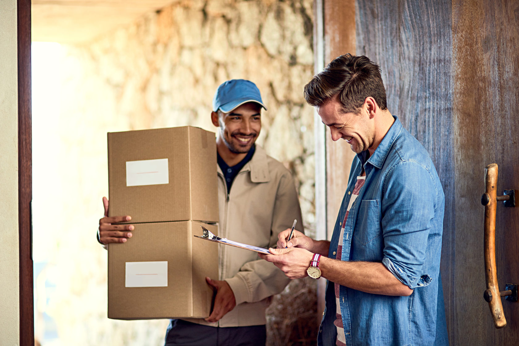 Happy customer signing for two boxes from delivery driver