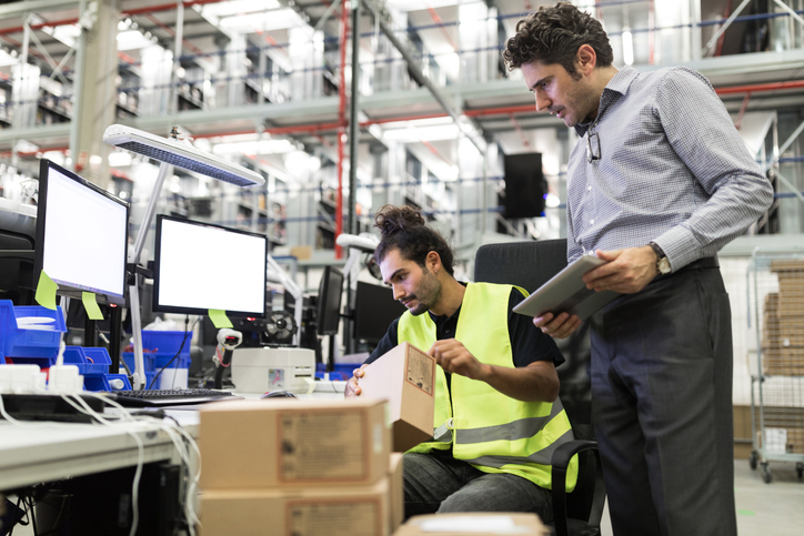 Two men label boxes in a distribution centre