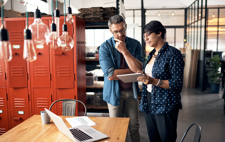 Office workers discussing work on a mobile tablet