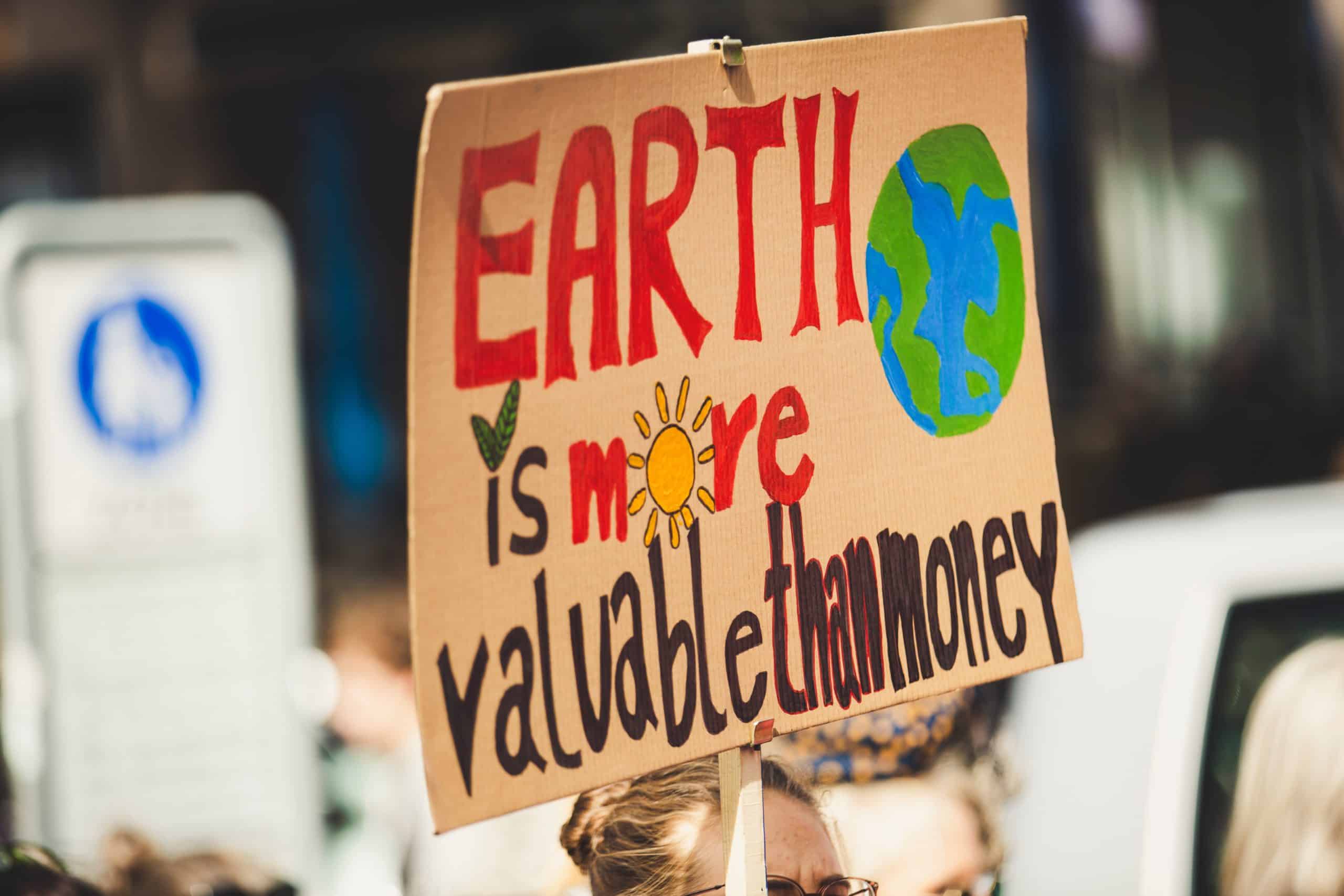 Plackard with "earth is more valuable than money" written on it