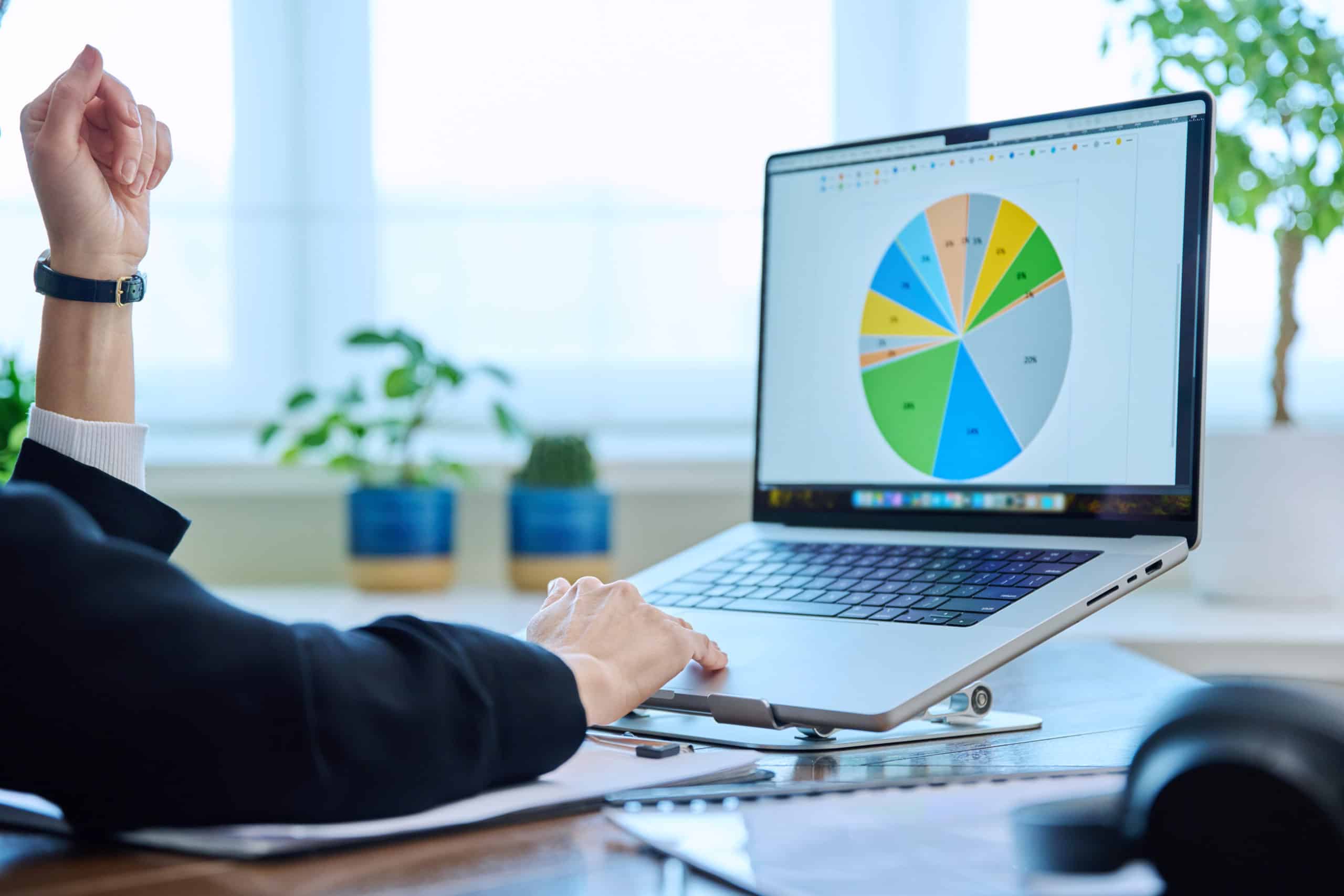 Office worker looking at laptop screen which shows a pie chart