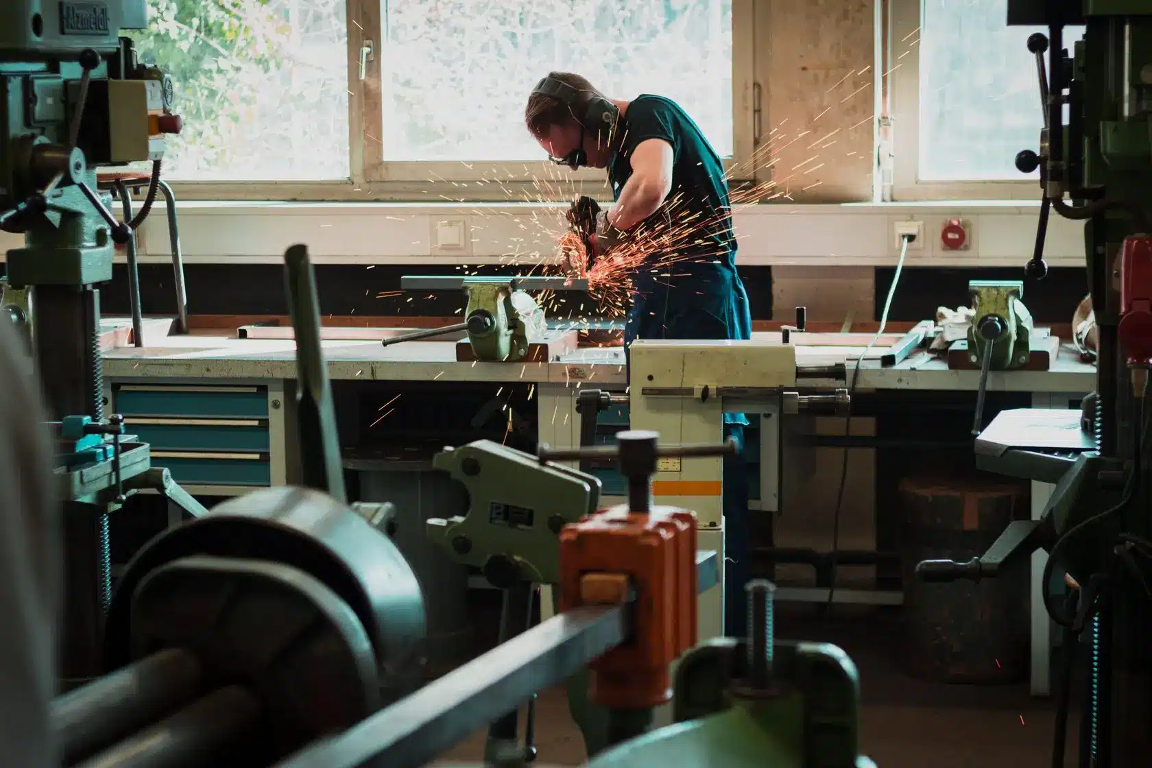 A man wearing PPE solders in a metal working studio.