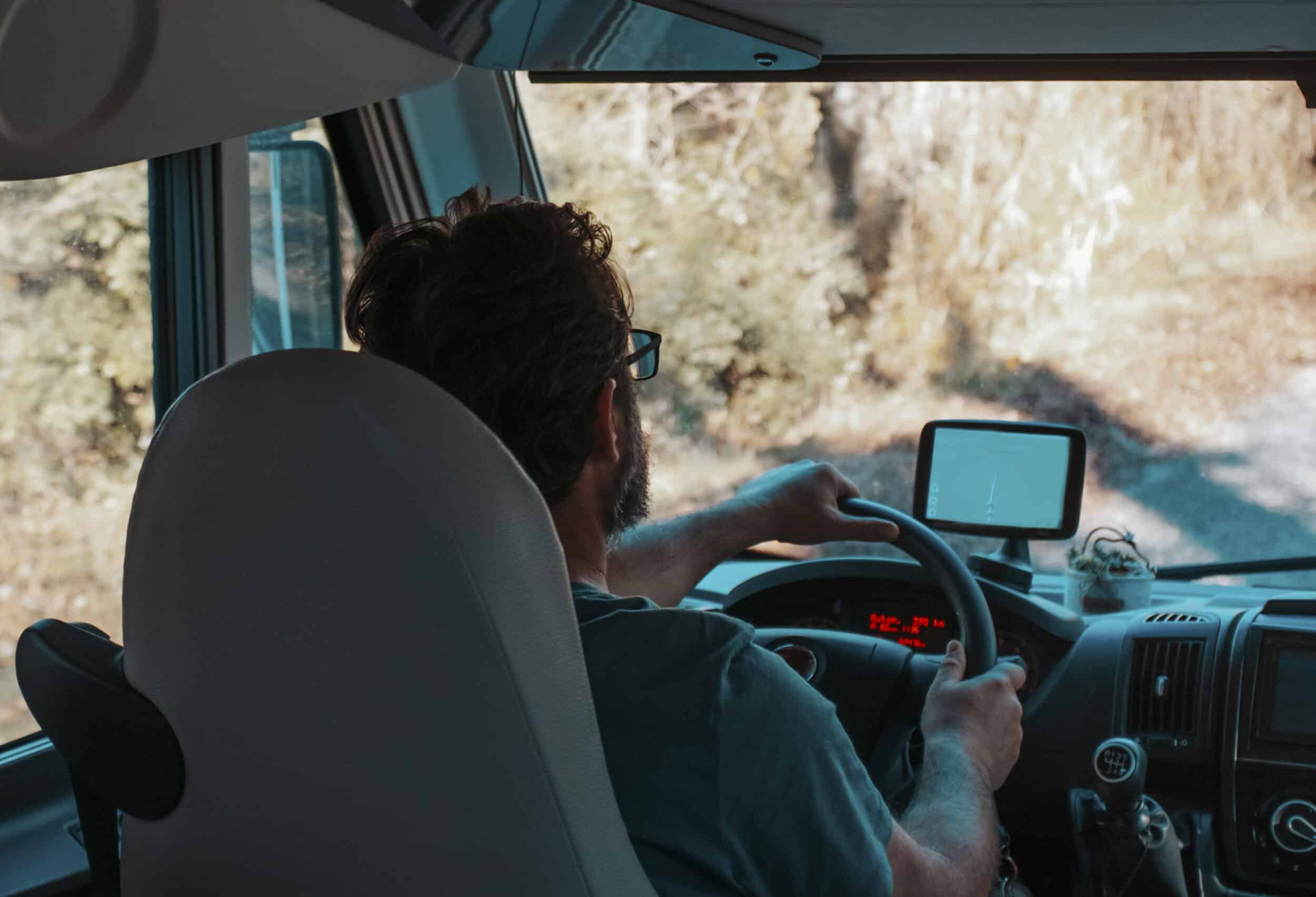 Delivery driver on the road with tracking technology in van, utilised with route planning solution