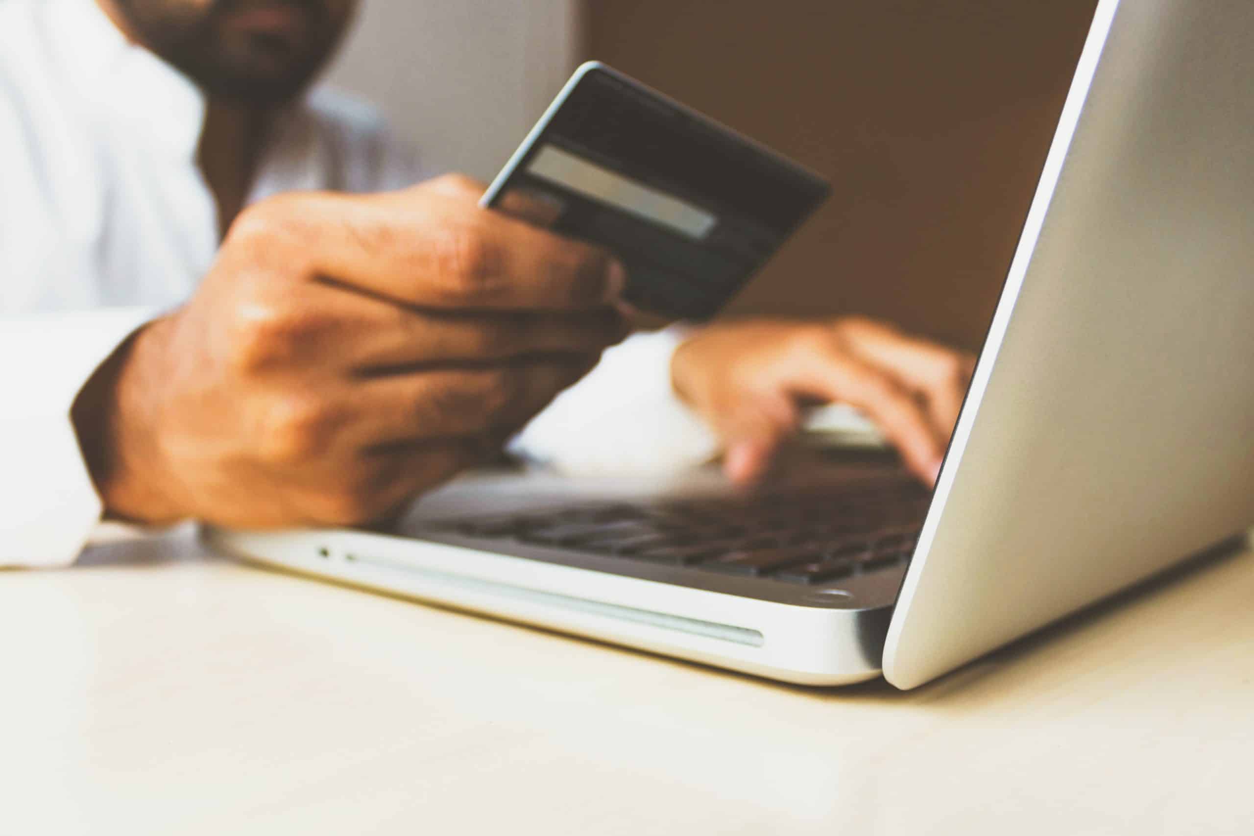 Person sitting in front of a laptop holding a credit card