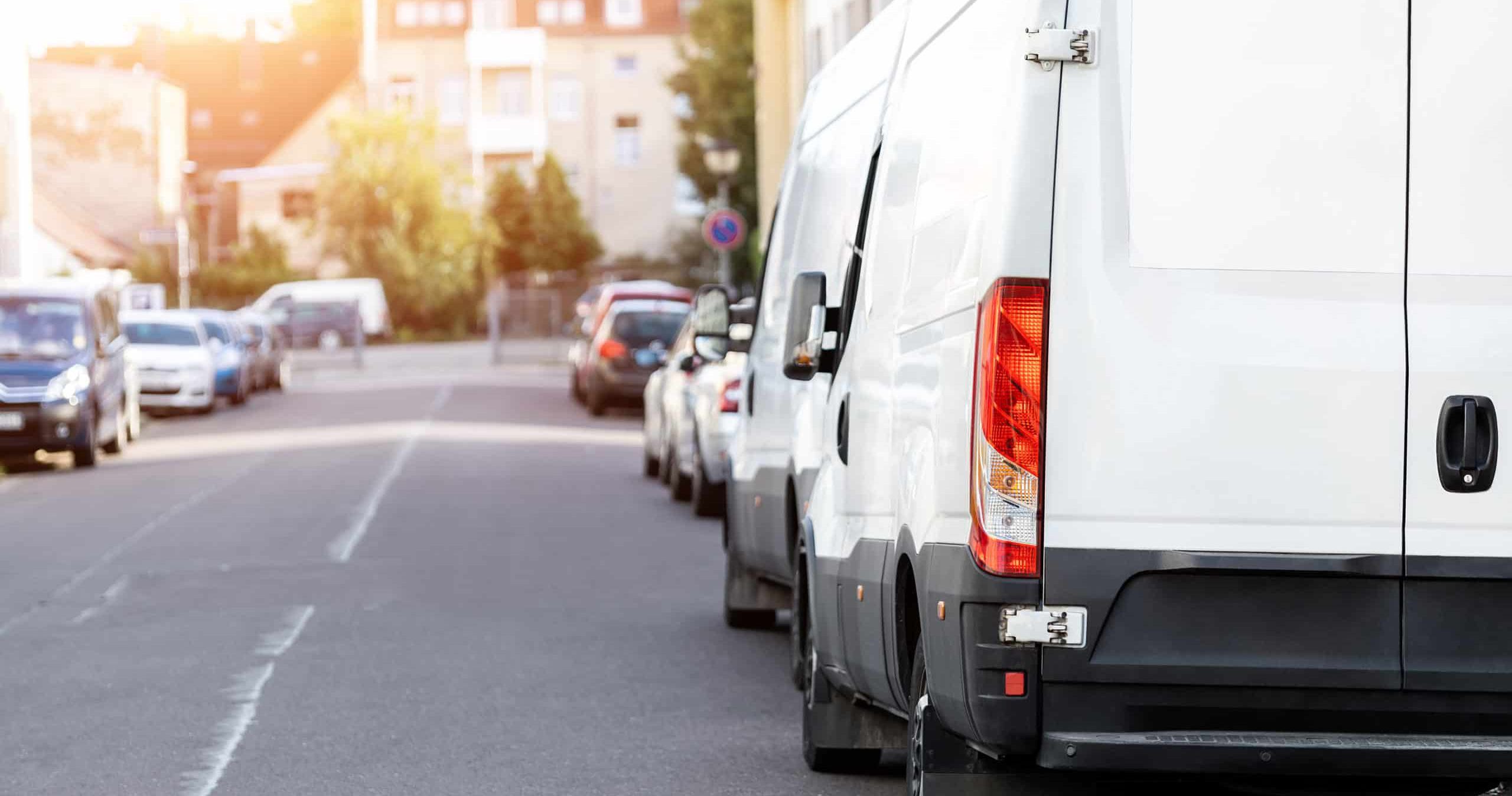 Small cargo delivery van parked in european city central district. Medium lorry minivan courier vehicle deliver package at residential office building in downtown area. Commercial shipping logistics.