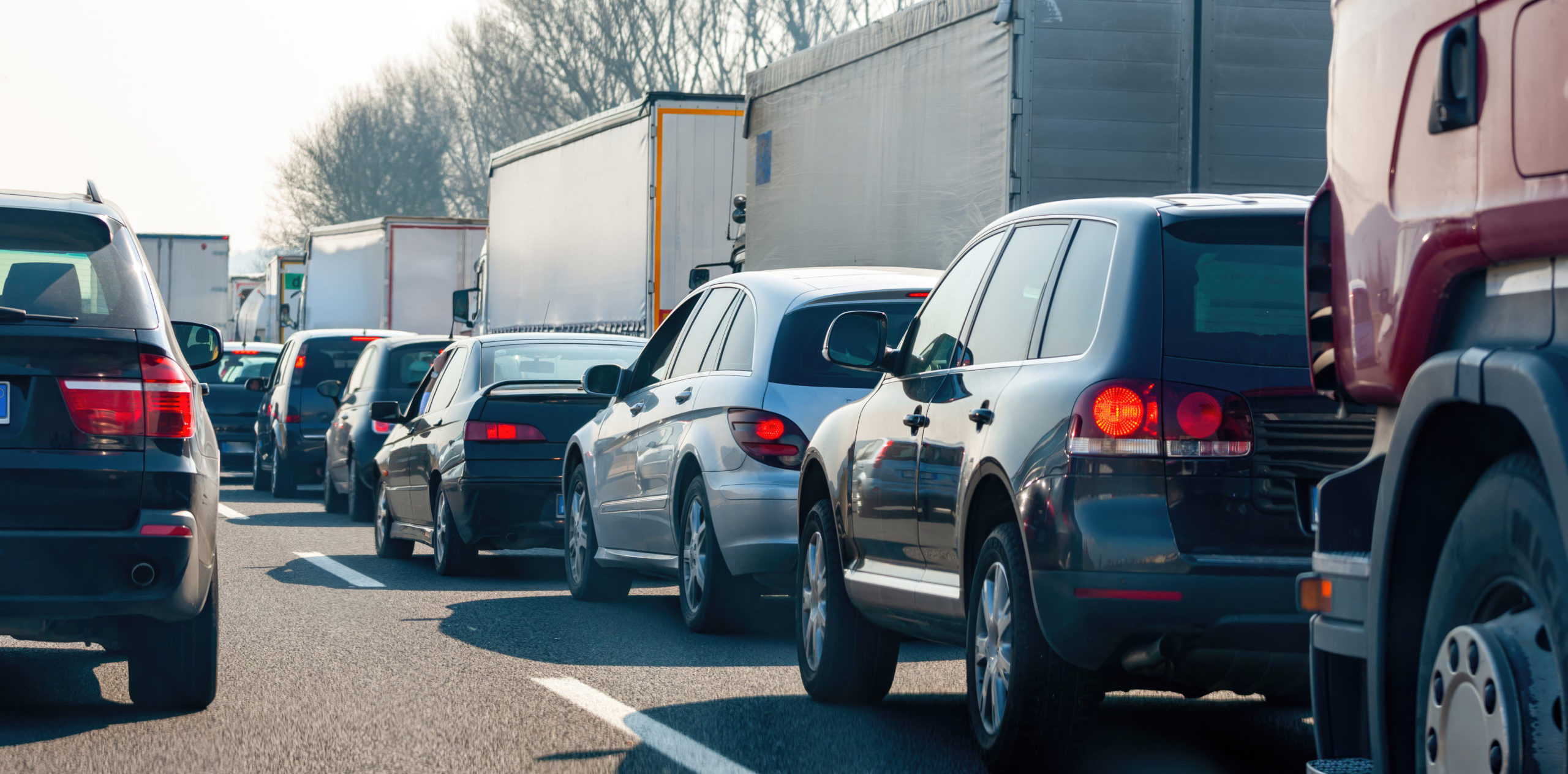 Cars and trucks are stuck in a traffic jam on a highway, creating congestion and delays for commuters