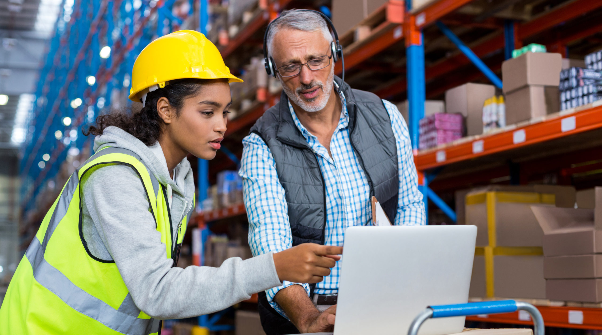 Warehouse workers using laptop in warehouse