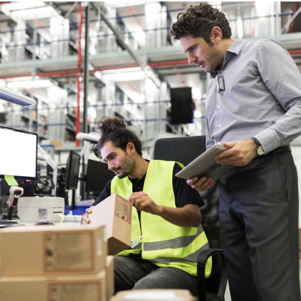 Warehouse workers discussing orders on their computer and mobile device