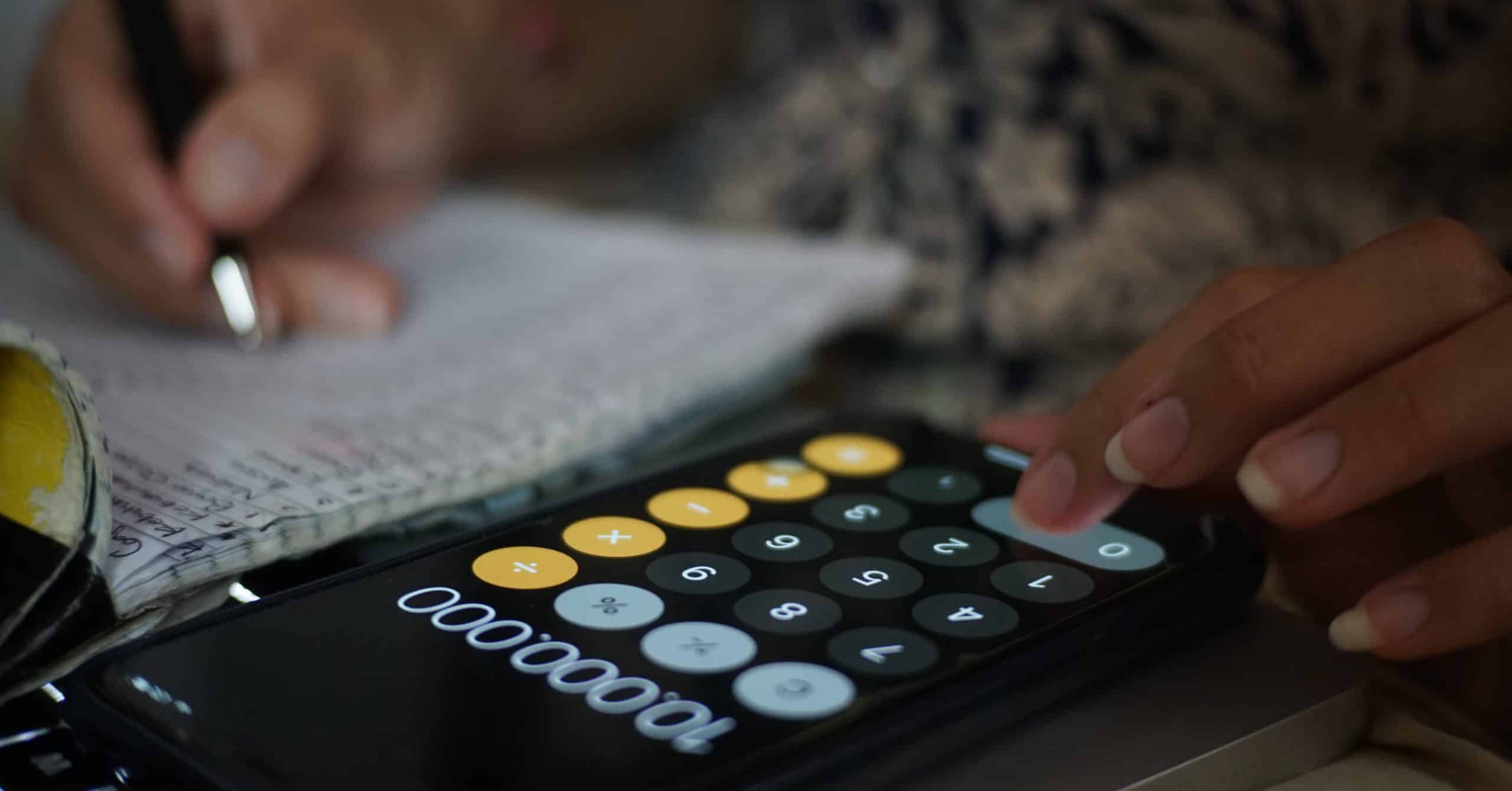 Person using calculator and writing on a notepad