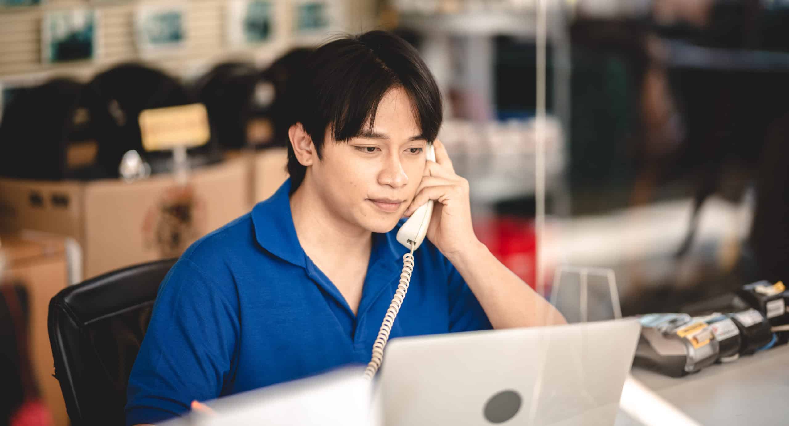 Male customer service worker on phone infront if apple laptop